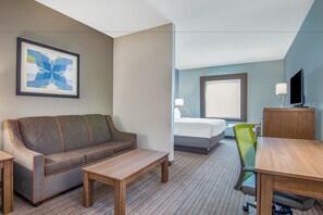 A hotel room with a sofa, a bed, a desk, and a chair. - Holiday Inn Express & Suites Stillwater - University Area by IHG (Stillwater)