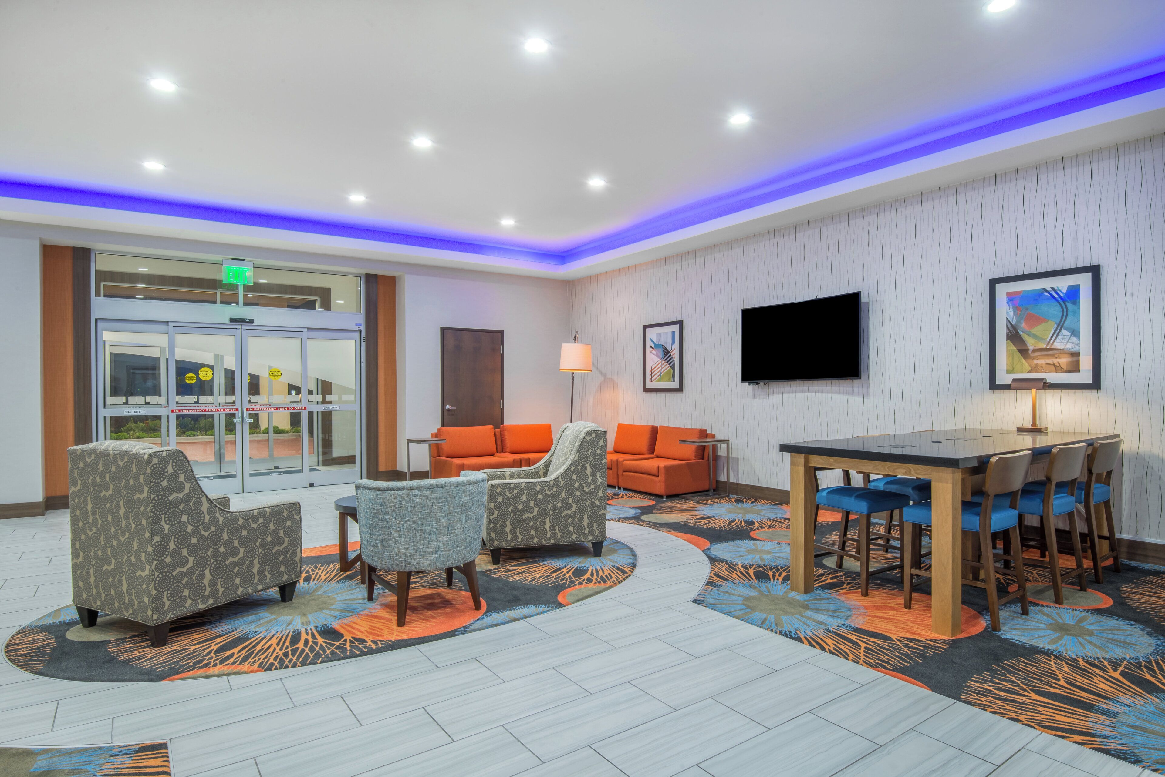 A hotel lobby with a reception desk, seating area, and a television.