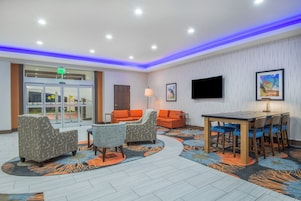 Un vestíbulo de hotel con recepción, zona de estar y televisor.