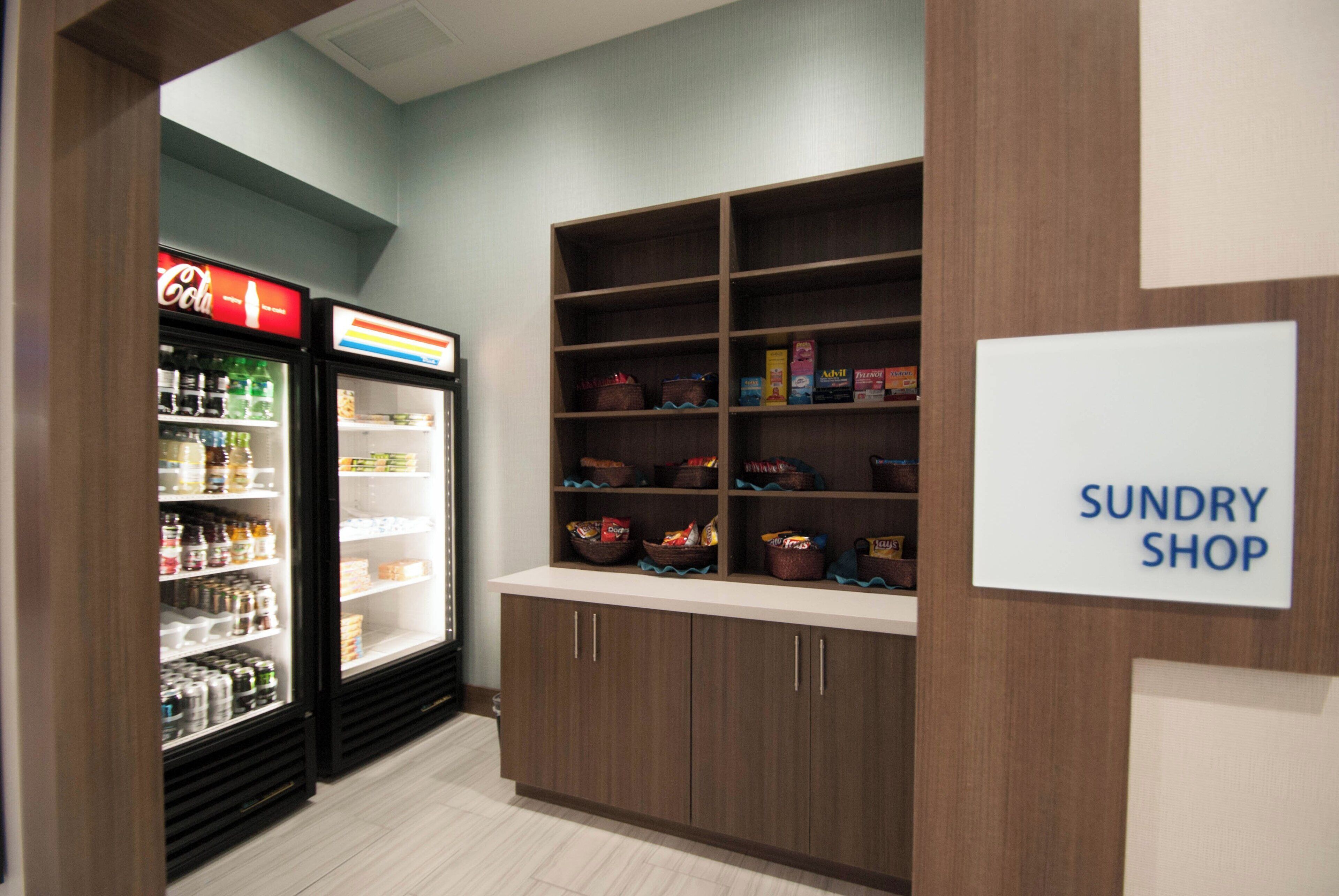 A grocery store interior with a refrigerated section on the left and a sundry shop on the right.