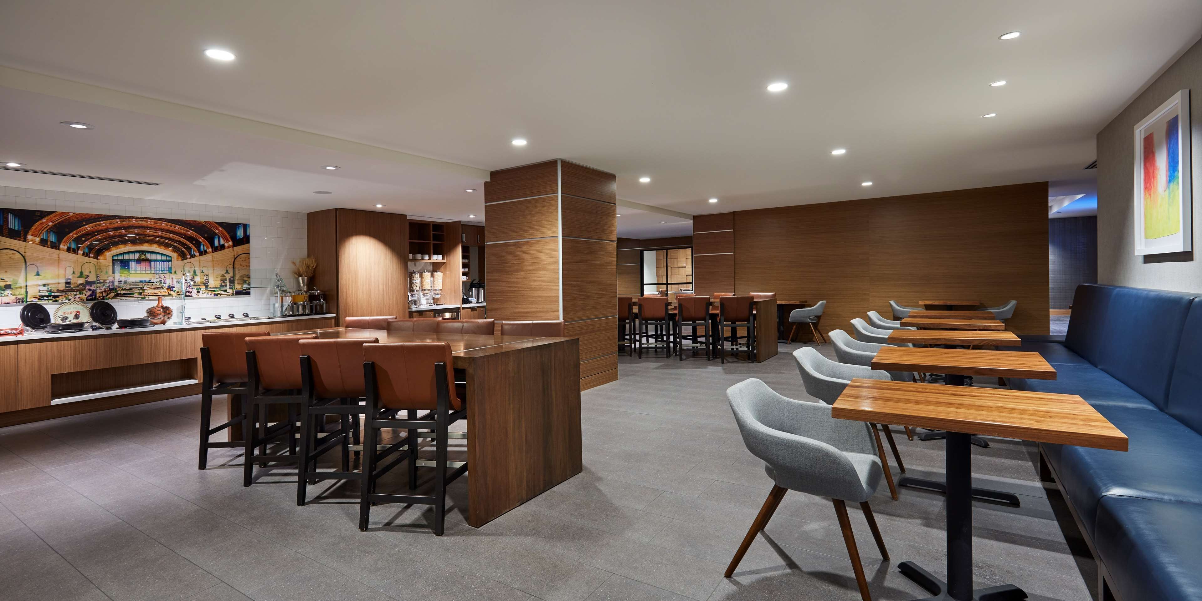 Een modern restaurantinterieur met een centrale bar, zitgedeelte en een muurschildering.