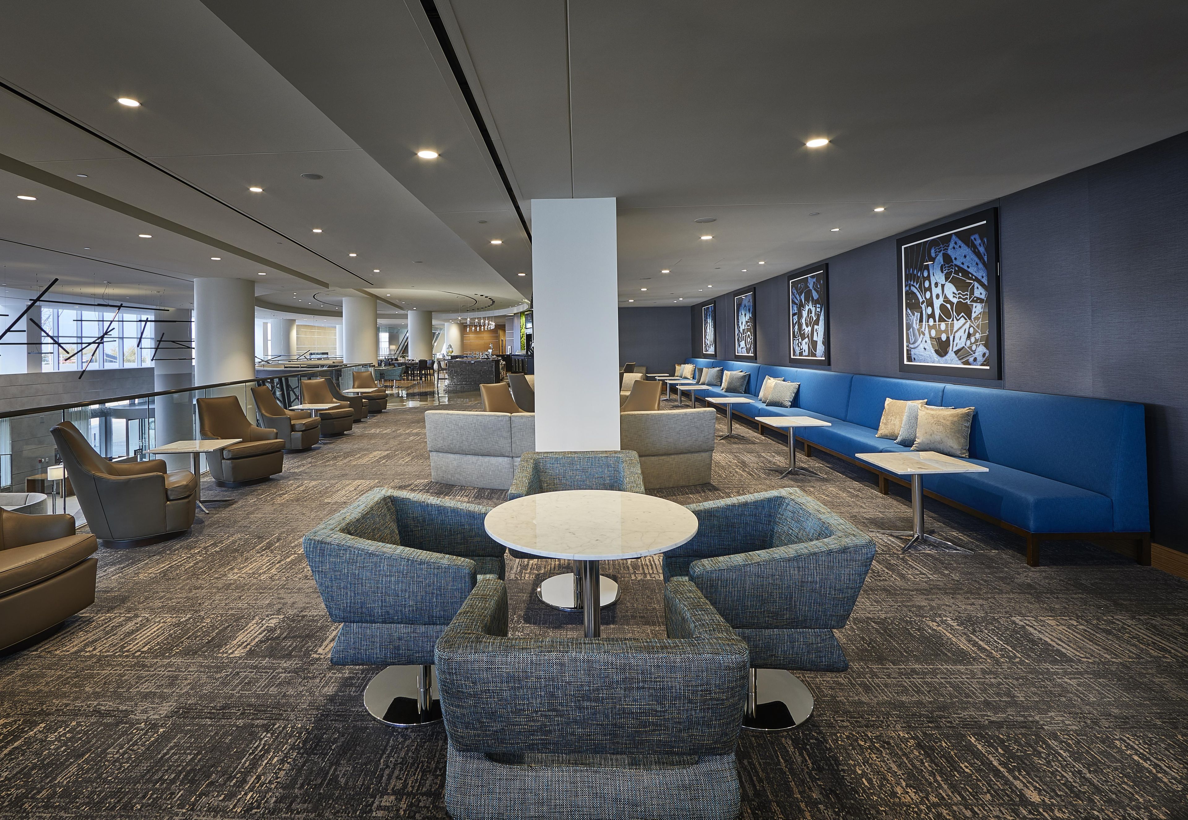 A modern lounge area with seating arrangements, a central table, and a view of the outside.
