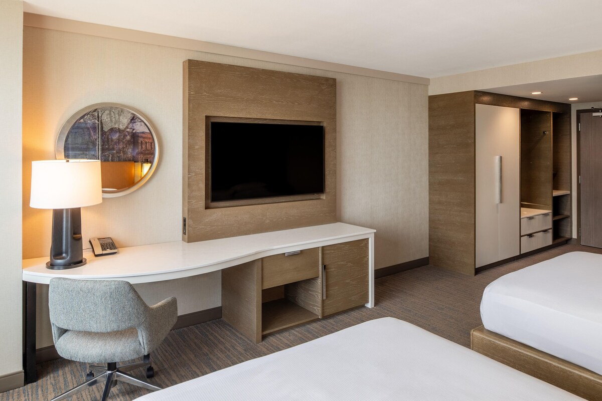 Ein Hotelzimmer mit Schreibtisch, Fernseher, Bett und begehbarer Kleiderschrank.
