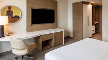 Ein Hotelzimmer mit Bett, Schreibtisch mit Stuhl, einem flachbildfernseher an der Wand und einem Kleiderschrank.