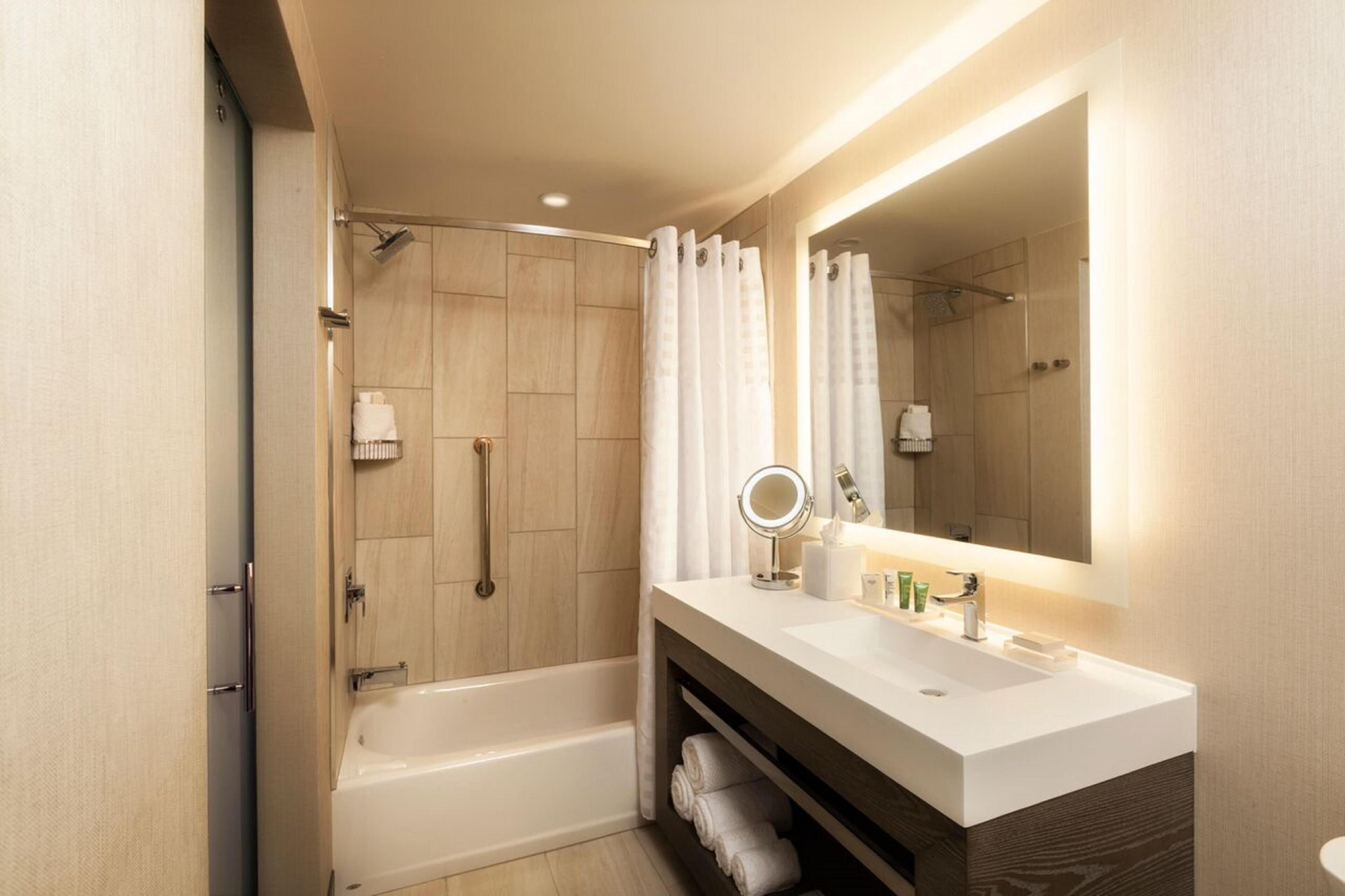 A modern bathroom with a bathtub, a shower, and a vanity with a mirror.