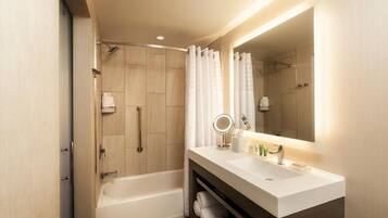 A modern bathroom with a bathtub, a shower, and a vanity with a mirror.