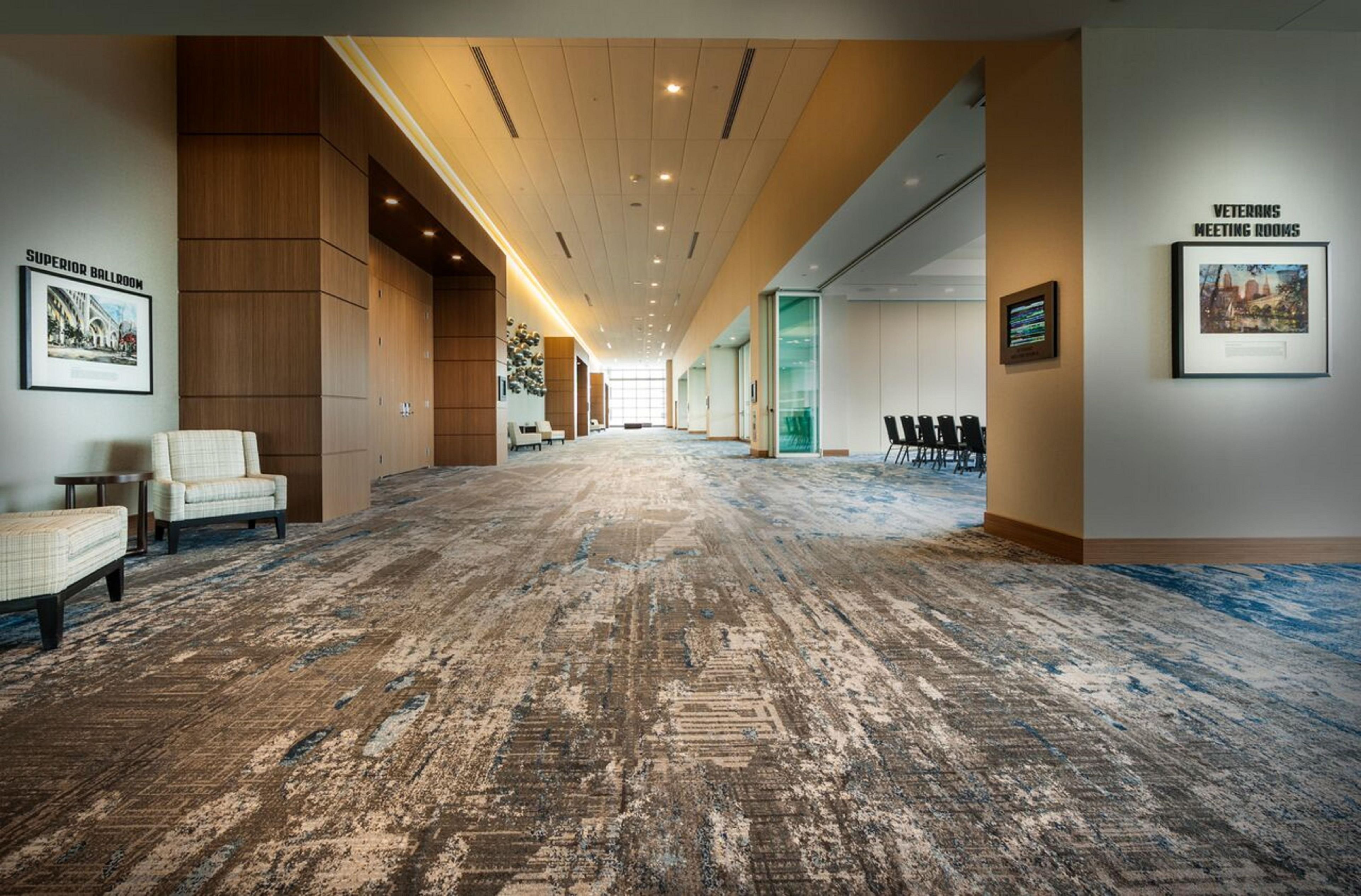 A spacious hallway with a patterned carpet, wooden paneling on the walls, and a framed picture labeled 'VETERANS MEETING ROOMS'.