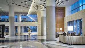 A spacious lobby with high ceilings, large windows, and modern furniture. - Hilton Cleveland Downtown (Cleveland)