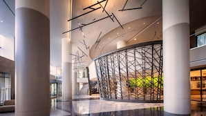 A spacious lobby with high ceilings, large columns, and a modern staircase. - Hilton Cleveland Downtown (Cleveland)