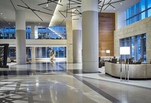 A spacious lobby with high ceilings, large windows, and a central sculpture. - Hilton Cleveland Downtown (Cleveland)