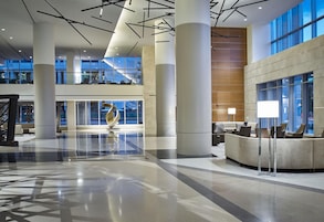 A spacious lobby with high ceilings, large windows, and a central sculpture.