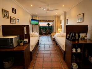 Habitación de hotel con dos camas, televisión, cafetera y vista al exterior.