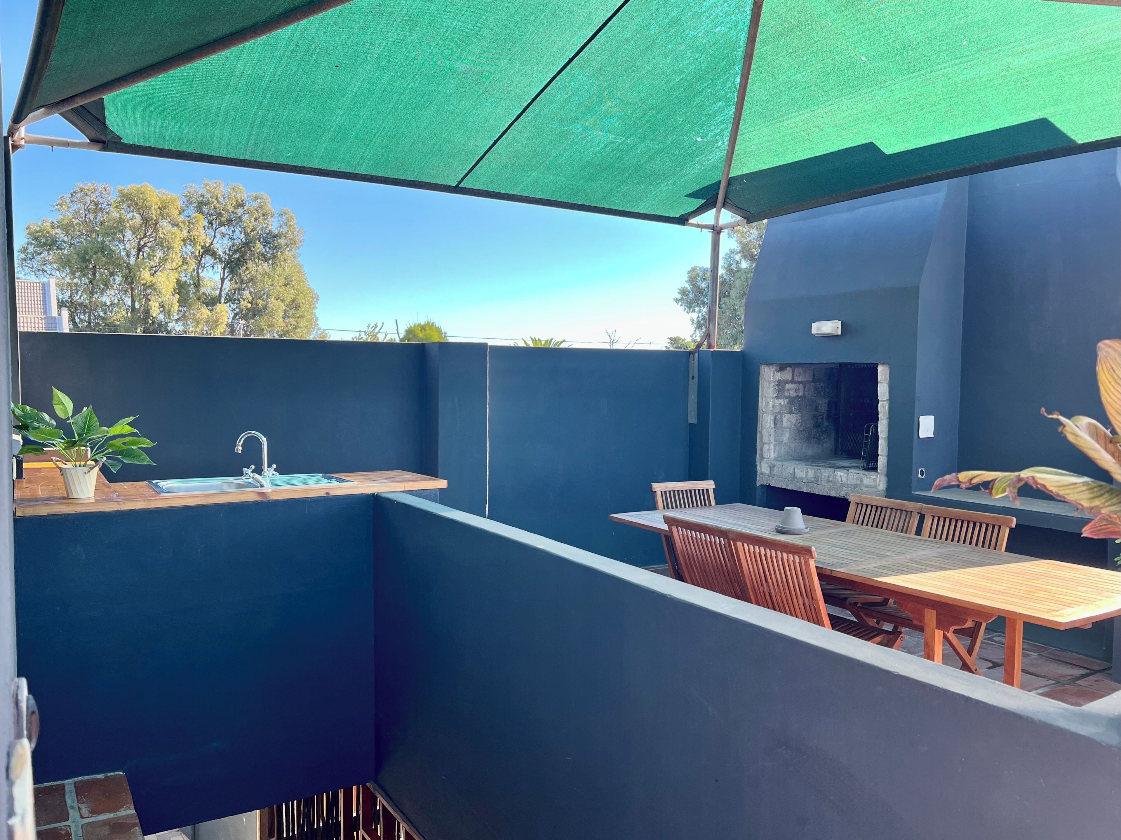 A covered outdoor area with a table and chairs, a sink, and a grill.