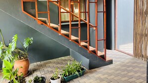 A staircase with a wooden railing, potted plants, and a door leading outside. - Goblin's Inn (St. Helena Bay)