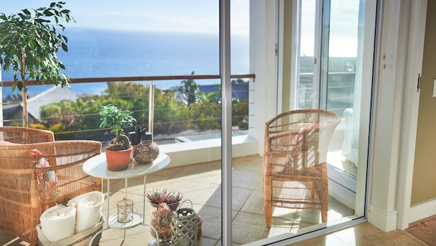 A balcony with wicker furniture, a small table, and potted plants. - Port Of Call (Cape Town)