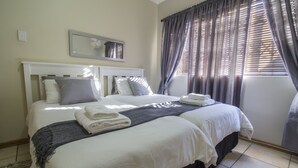 A double bed with white linens, a dark headboard, and a grey throw blanket. - Madiolyn (Jeffreys Bay)