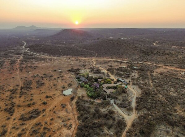 An aerial view of a desert landscape with a small cluster of buildings surrounded by sparse vegetation and winding roads.