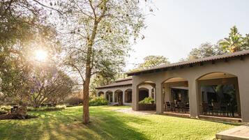 A building with a covered patio area, outdoor seating, and a well-maintained lawn.