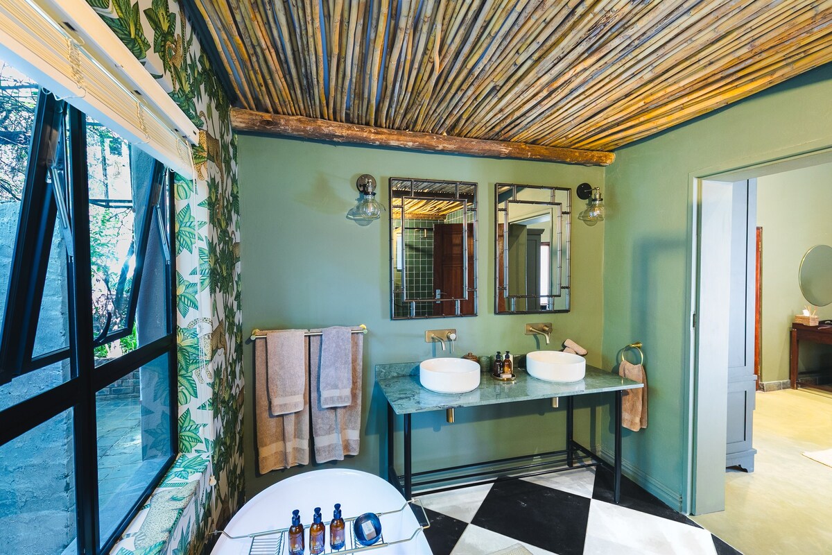 A bathroom with a large window, two sinks, a mirror, and a ceiling made of bamboo.