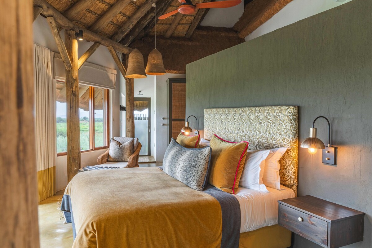A bedroom with a large bed, a nightstand, and a wall-mounted lamp.