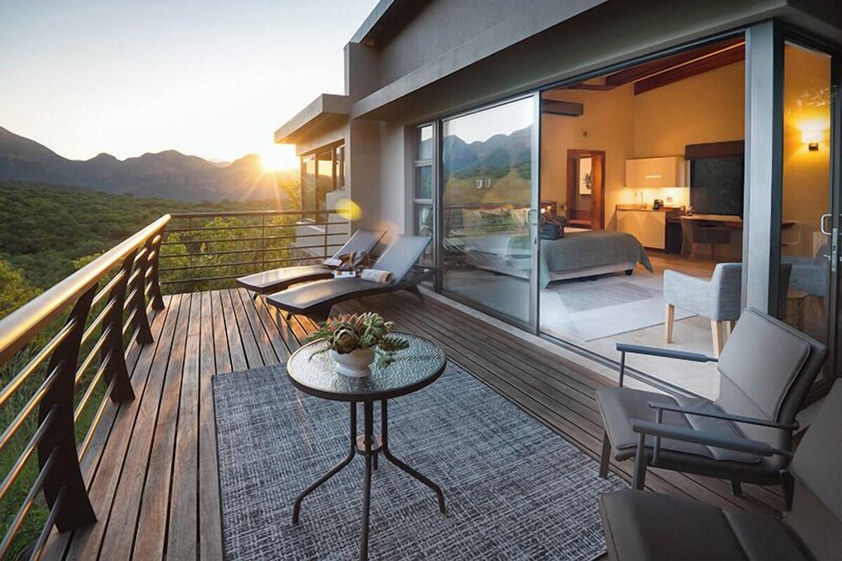 A modern hotel room with a balcony overlooking a mountainous landscape.