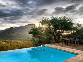 Una piscina al aire libre, sombrillas, sillones reclinables de piscina