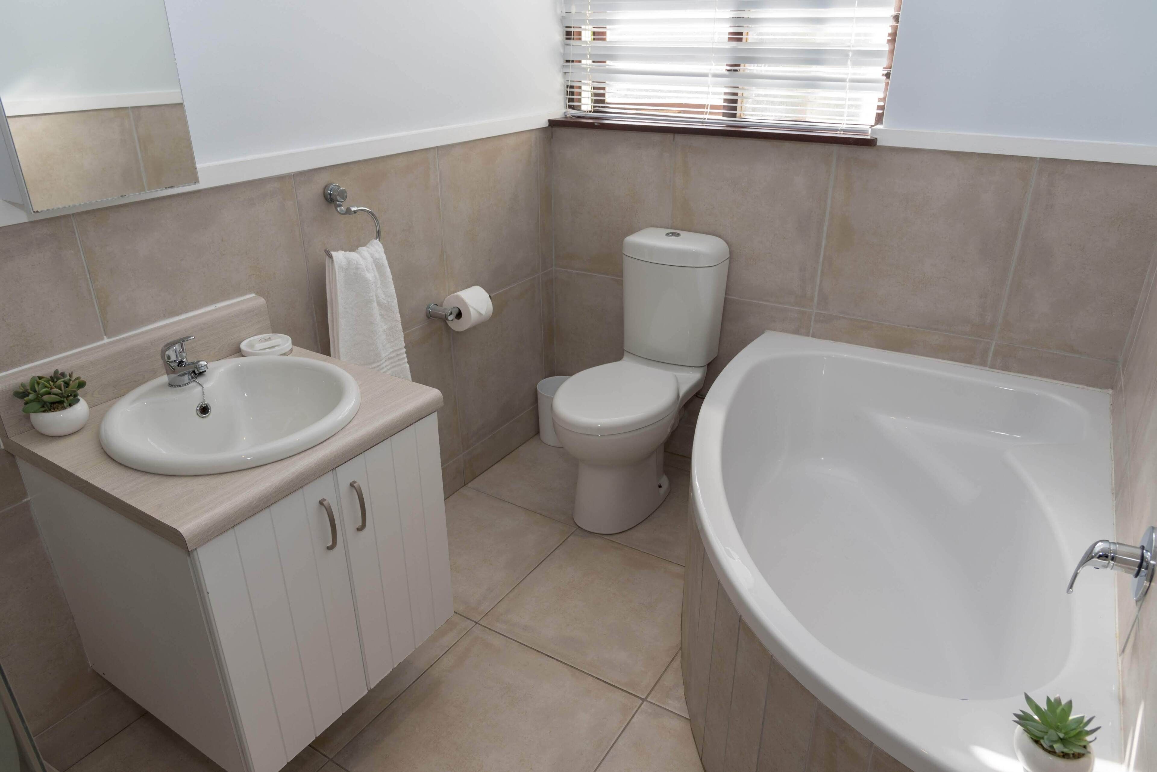 A modern bathroom with a sink, toilet, and bathtub.