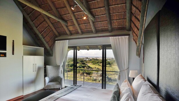 Une chambre avec un grand lit, une chaise, une armoire et une vue sur le paysage.