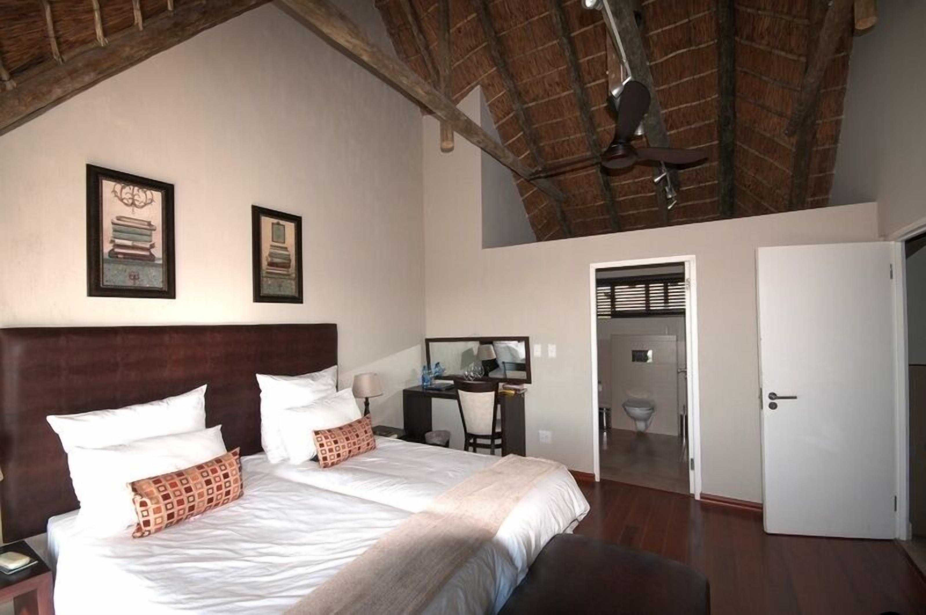 Un dormitorio con una cama grande, un escritorio y una silla. Hay una puerta que da a un baño.