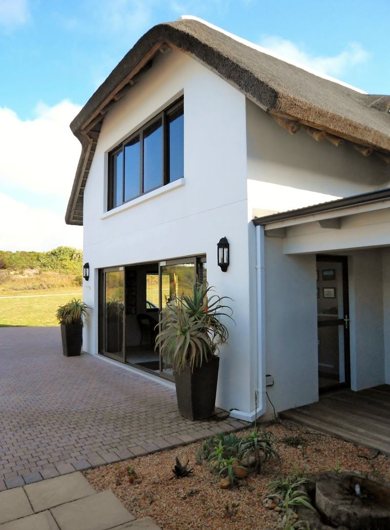 A two-story house with a large garage door, a covered patio, and a driveway.