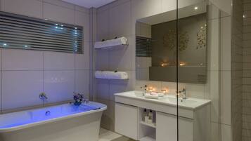 A modern bathroom with a freestanding bathtub, a vanity with a mirror, and a shelf with towels.