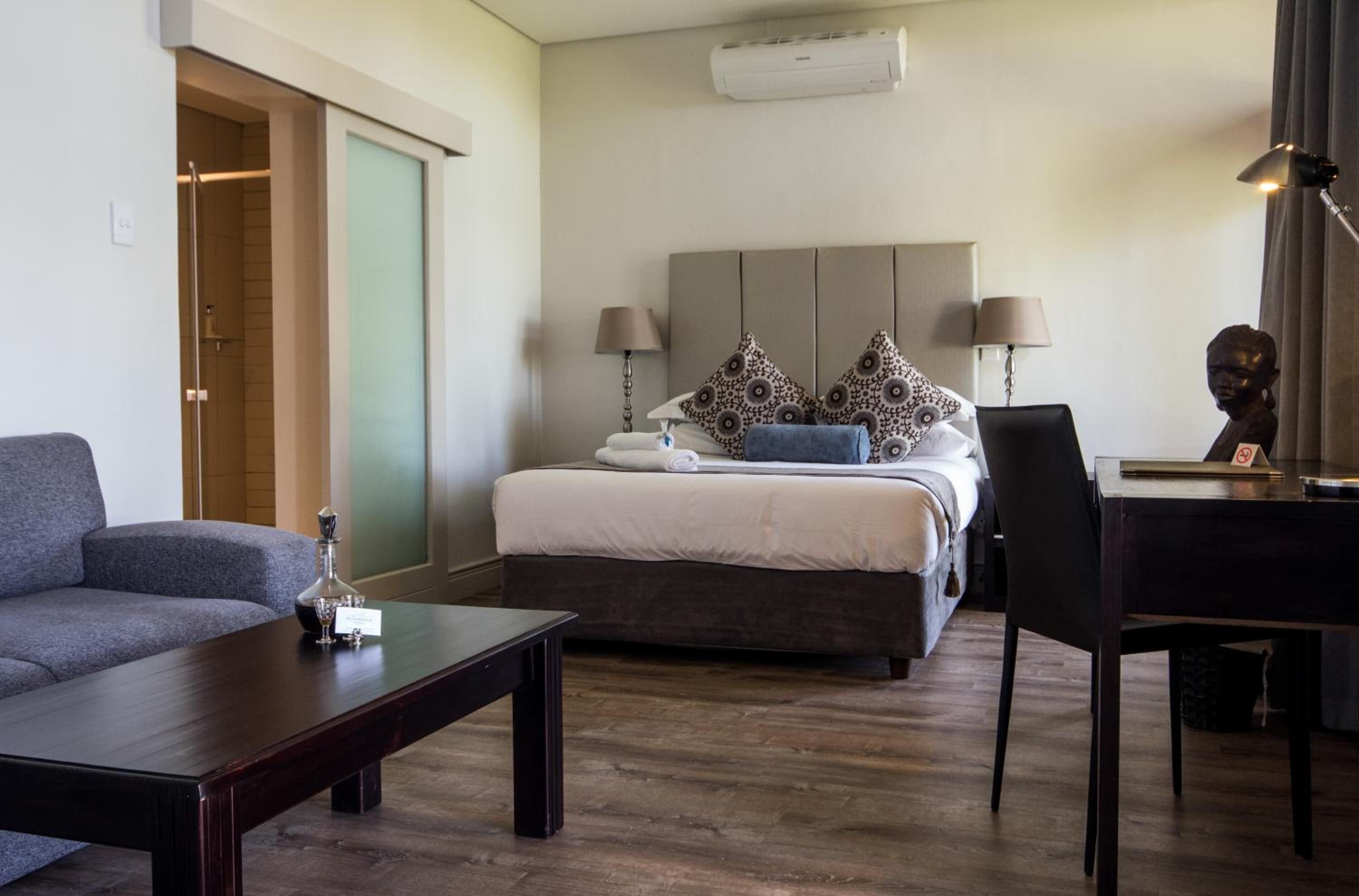 Une chambre d’hôtel comprenant un lit, deux lampes de chevet, un bureau avec une chaise, un canapé et une table basse.