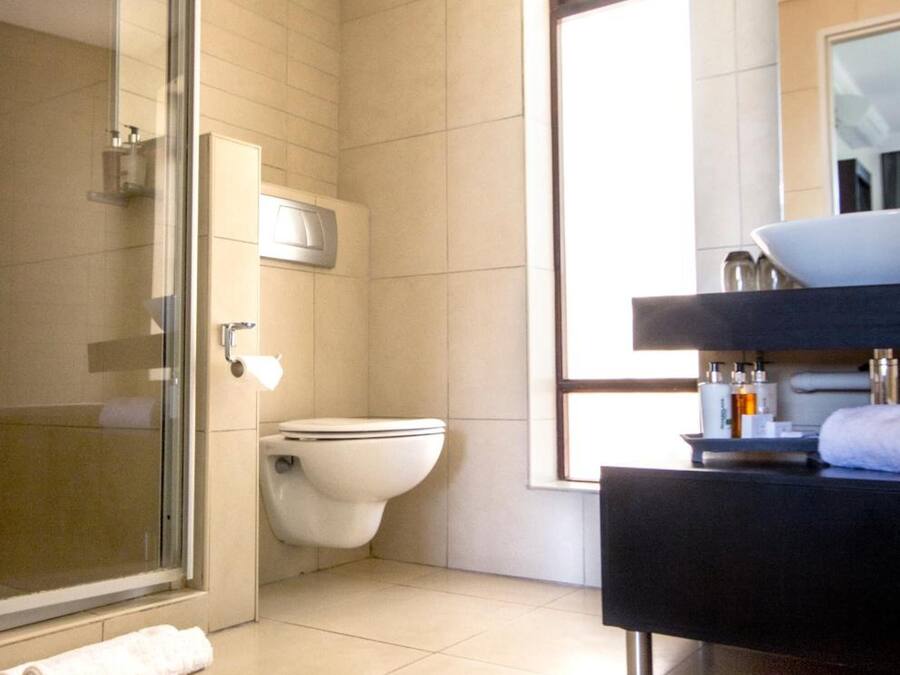 A bathroom with a glass shower enclosure, a toilet, and a vanity with a sink.