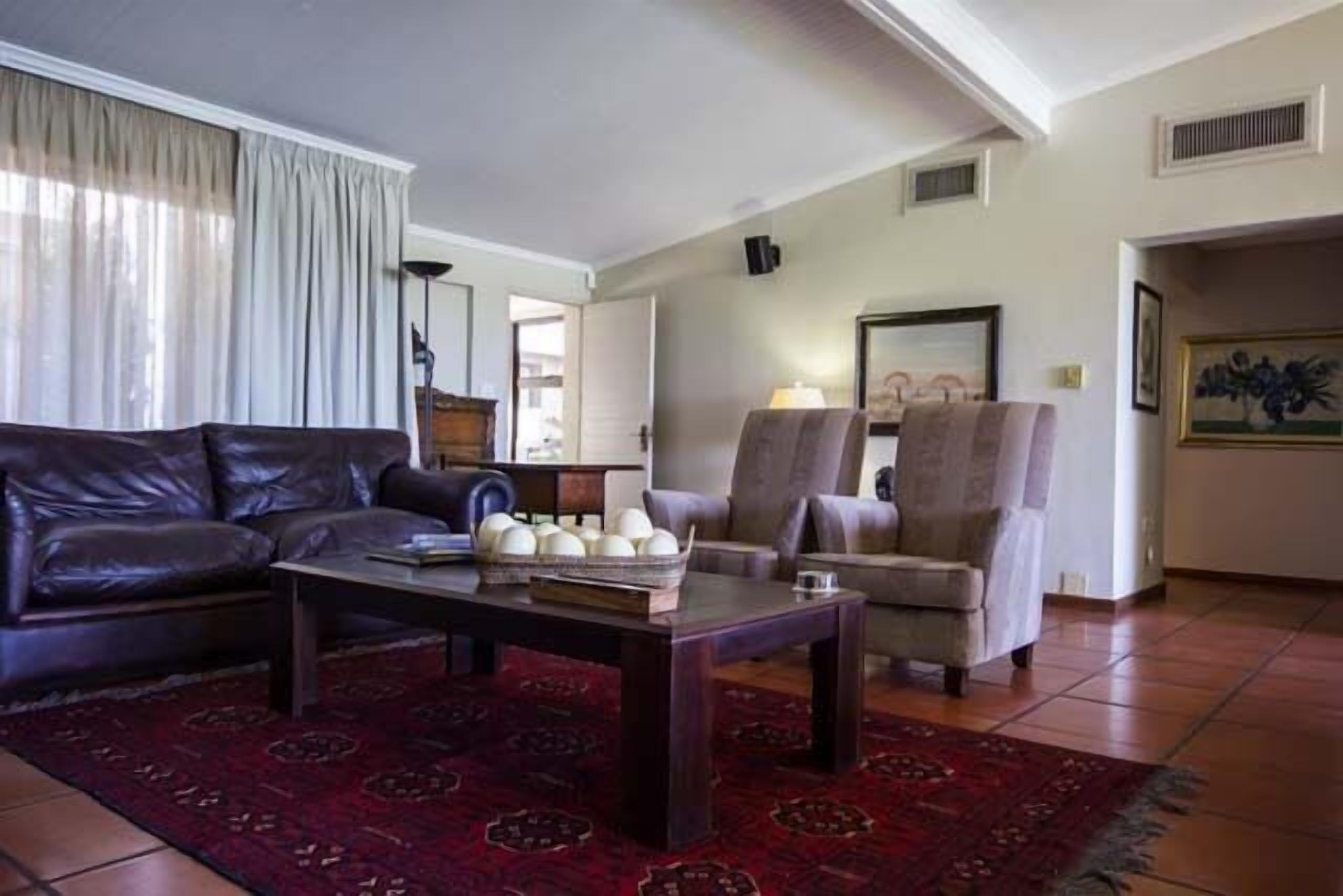 A living room with a dark leather sofa, a wooden coffee table, and a patterned rug.