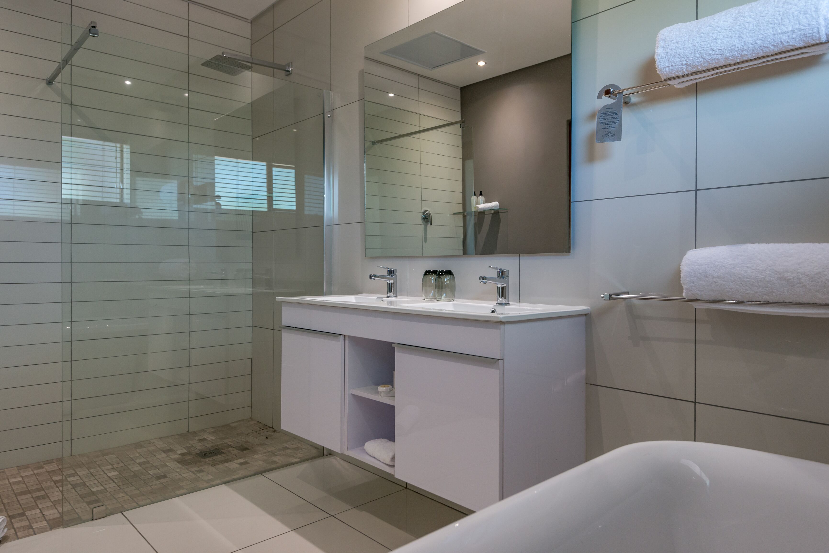 A modern bathroom with a glass-enclosed shower, a white vanity with a mirror, and a bathtub.