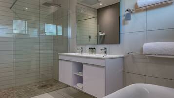 A modern bathroom with a glass-enclosed shower, a white vanity with a mirror, and a bathtub.