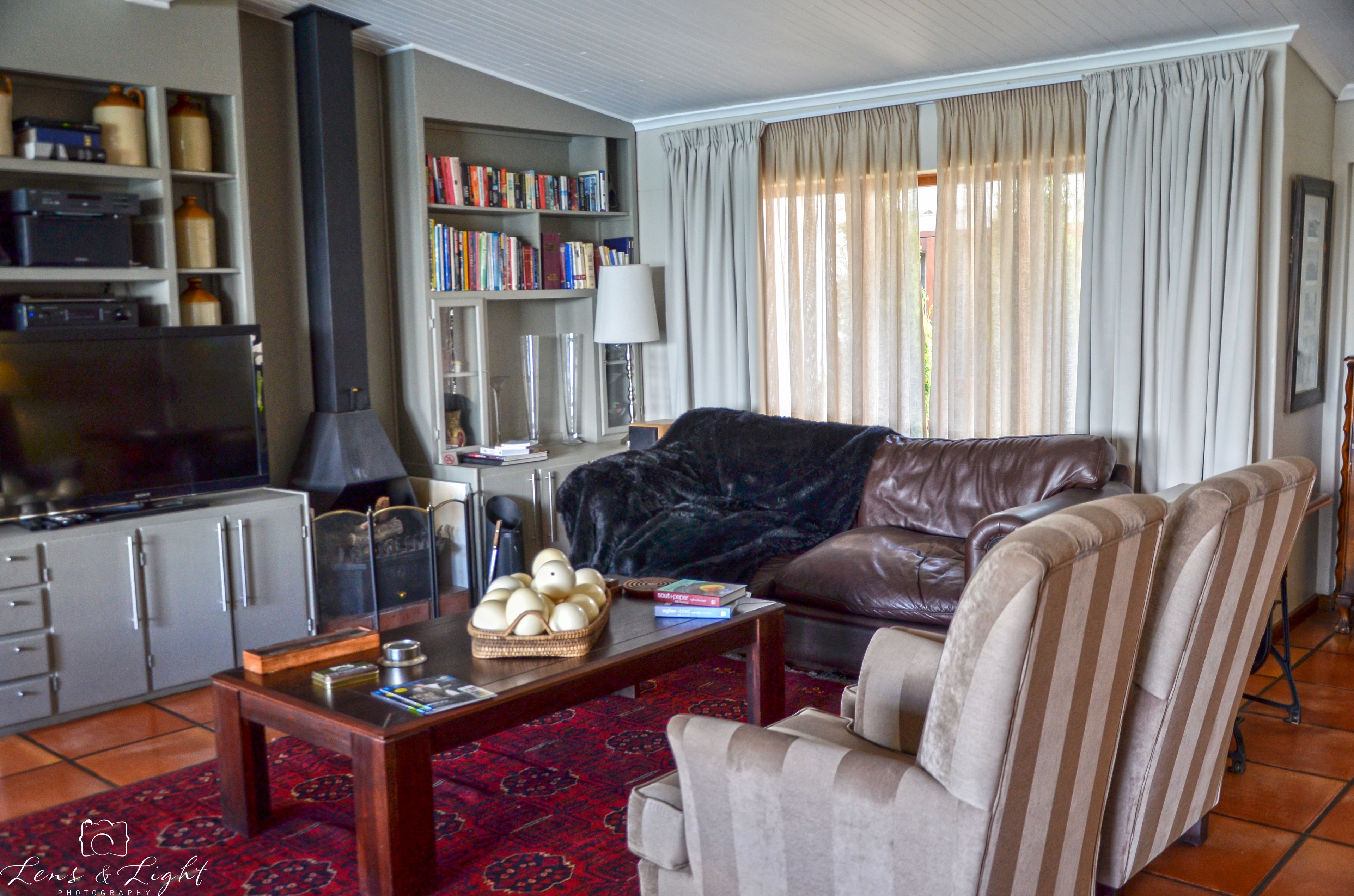 Ein Wohnzimmer mit einer Ledersofa, einem Couchtisch, einem Bücherregal, einem Fernseher und einem Kamin.