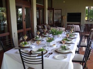 A long dining table set for a meal with multiple chairs, a white tablecloth, and various dishes and drinks. - River Place Manor (Upington)