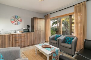 Um espaço compacto para viver, com cozinha compacta, um sofá, uma mesa de centro e uma janela grande com cortinas.