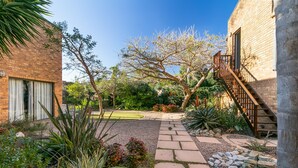 A courtyard with a brick building, a stone pathway, and various plants. - Overmeer Guest House (Knysna)