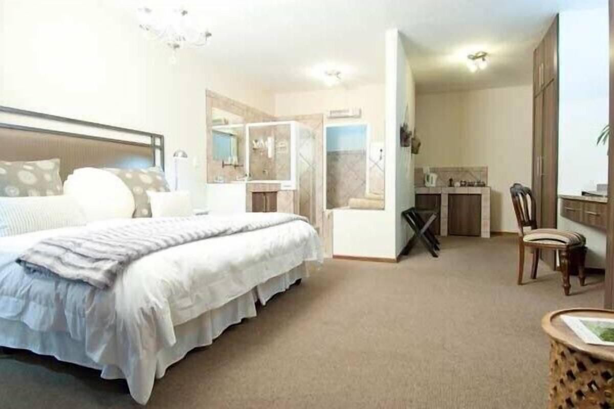 A bedroom with a large bed, a desk, and a chair, and a bathroom with a shower and a toilet.