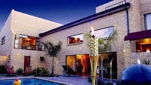 A modern hotel with a pool area, outdoor seating, and a well-lit entrance. - Overmeer Guest House (Knysna)