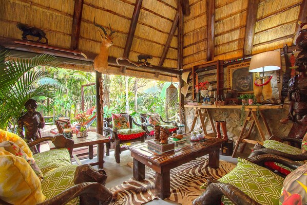 A room with a thatched roof, wooden furniture, and various decorative items including animal sculptures and a framed picture.