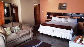 A bedroom with a bed, a sofa, a clock, and a painting on the wall. - Acre of Africa Guest Venue (Boksburg)
