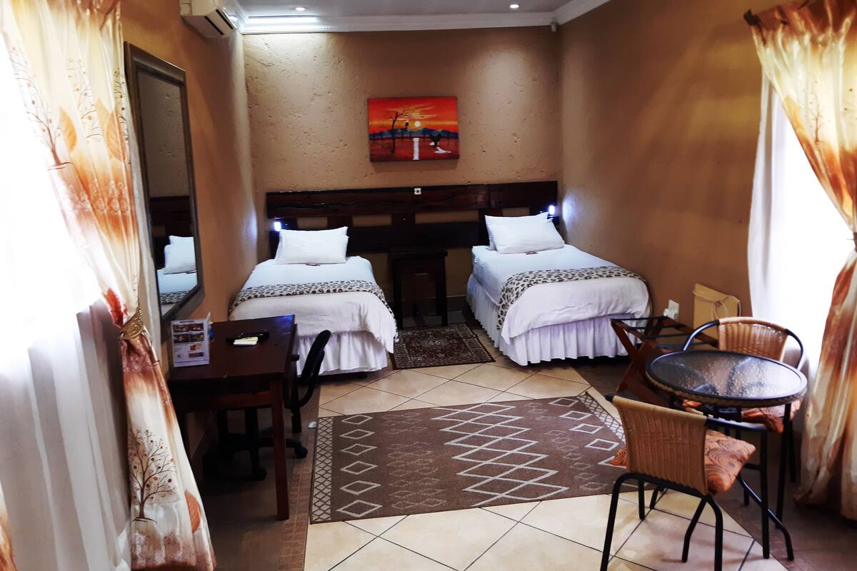 Une chambre d’hôtel avec deux lits, un bureau, une chaise, une table et un tapis.