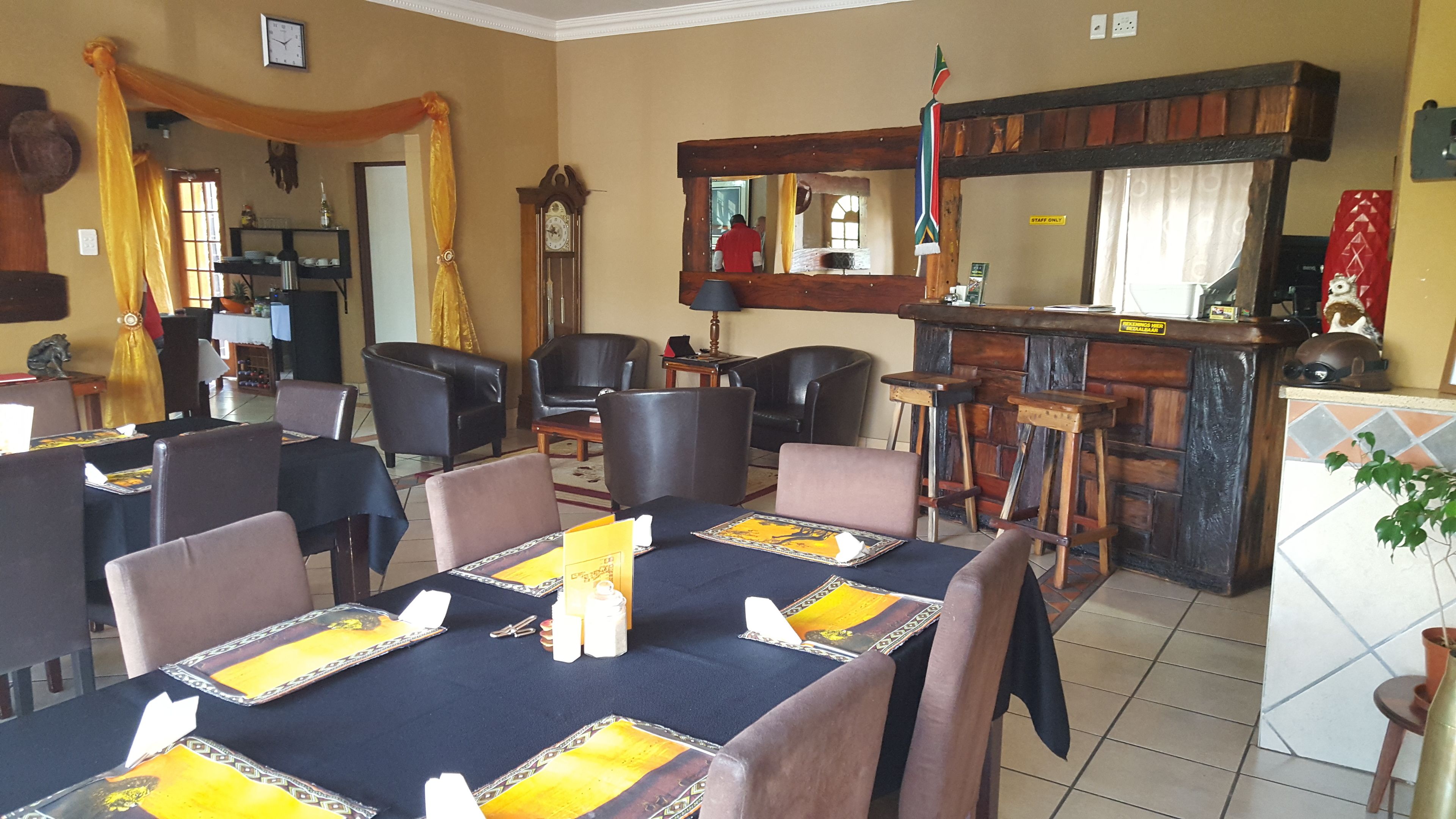 A restaurant with a bar area, multiple dining tables with chairs, and a counter with stools.