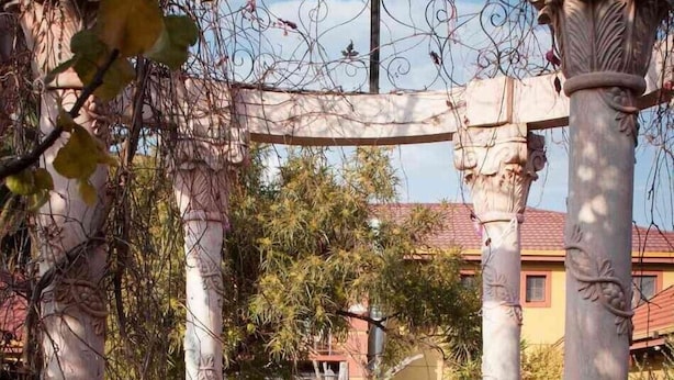An outdoor seating area with a pergola structure, a round table, and rows of chairs. - Acre of Africa Guest Venue (Boksburg)