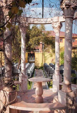 An outdoor seating area with a pergola structure, a round table, and rows of chairs. - Acre of Africa Guest Venue (Boksburg)