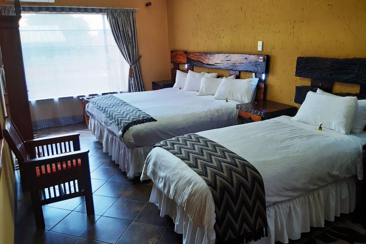 Une chambre d’hôtel avec deux lits, une tête de lit en bois et un banc.