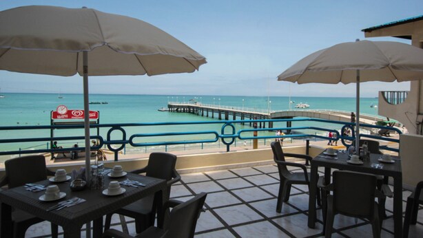 A seaside restaurant with outdoor seating, a pier, and a view of the ocean. - Blue Bay Hotel (Salinas)